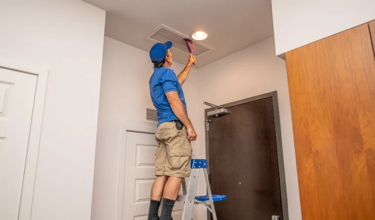 a person on ladder cleaning the home air vents